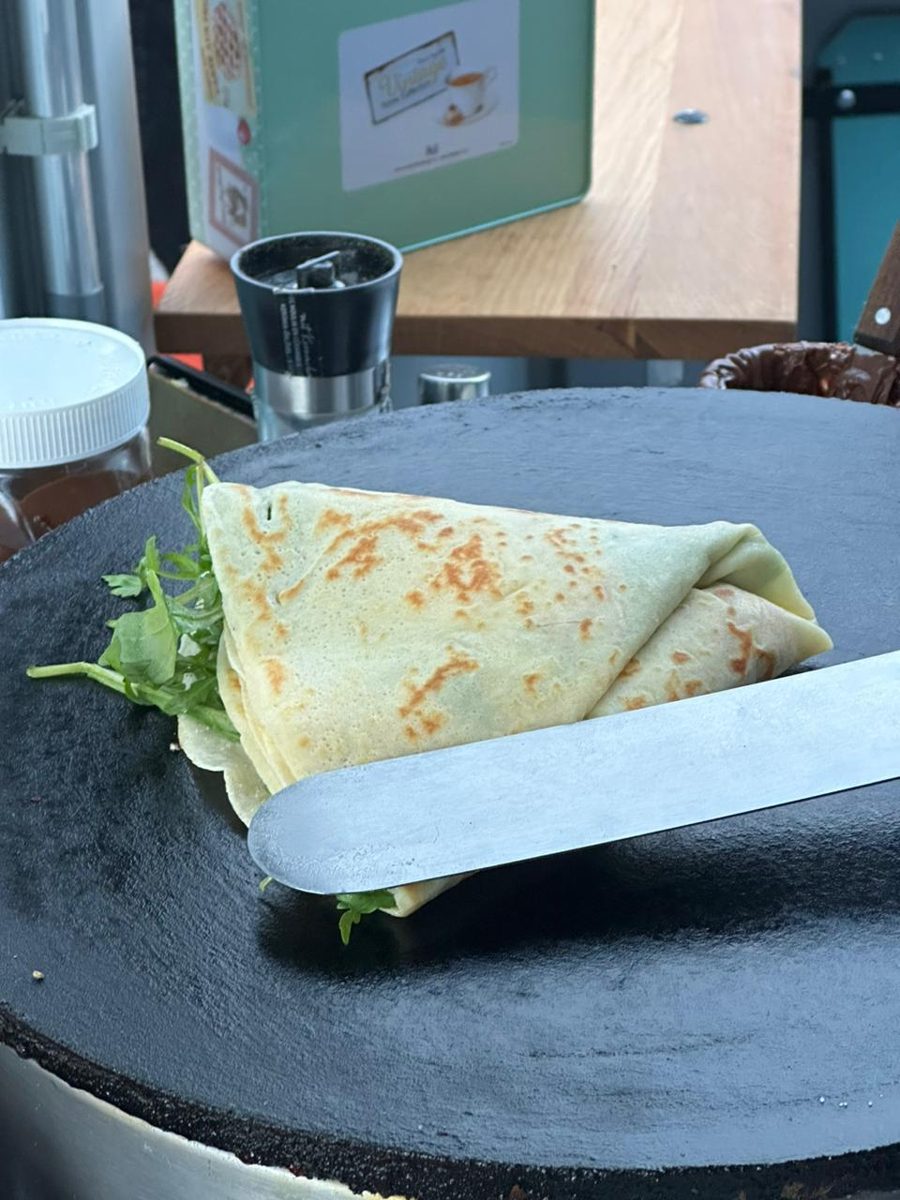 A savory crêpe with rocket being folded on the hot plate