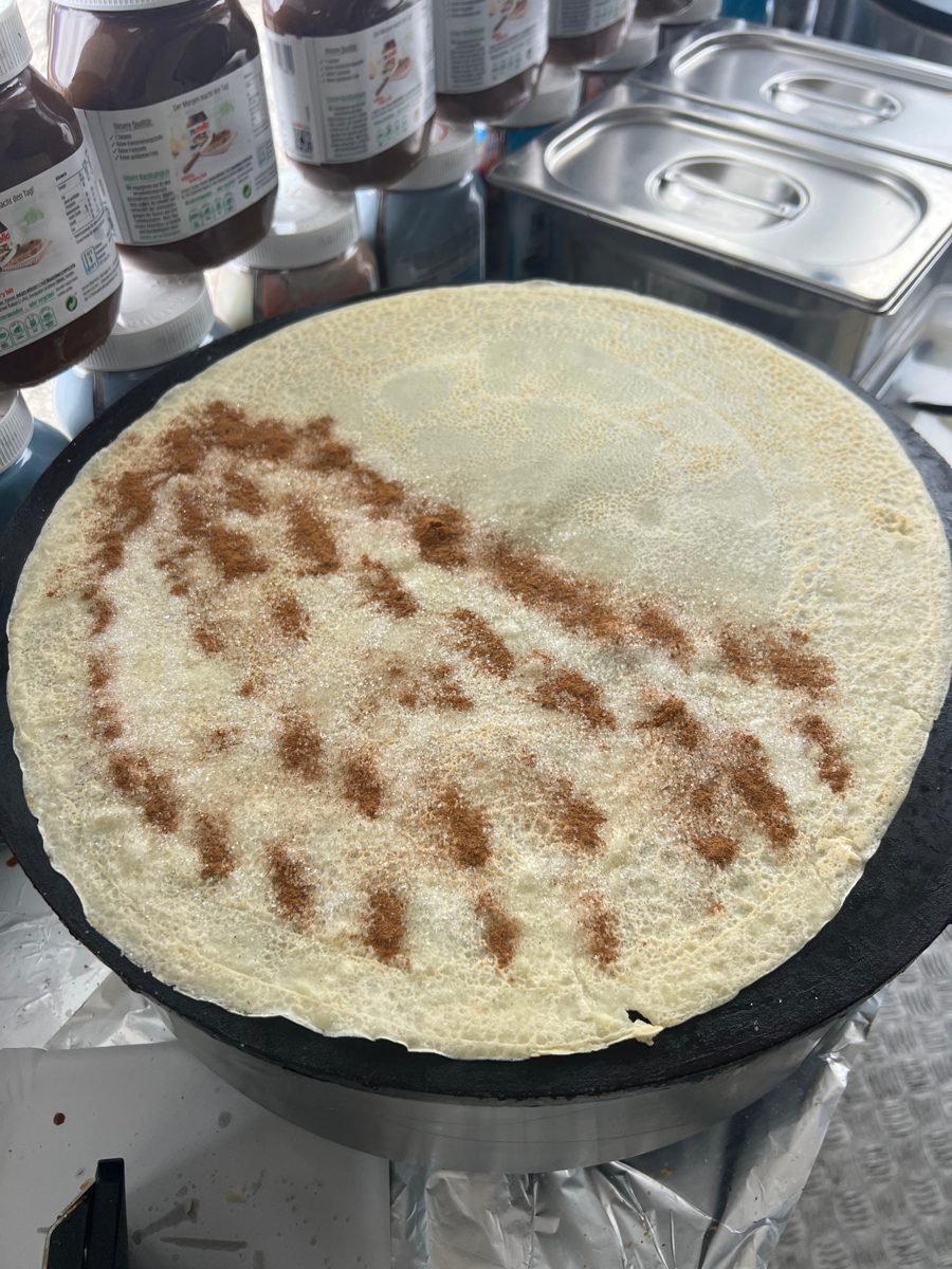 A crêpe sprinkled with sugar and cinnamon on the hot plate