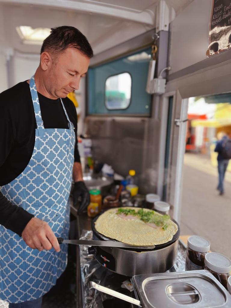 Making a savory crêpe on the hot plate inside the trailer